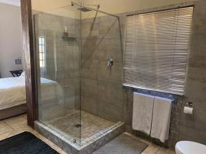 a bathroom with a shower with a glass door at Douglas Villas in Tzaneen +49 photos