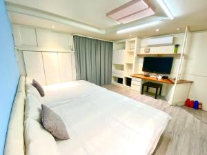 a bedroom with a large white bed and a television at Fengjia Pig's House in Taichung