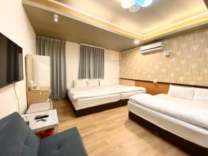 a hotel room with two beds and a couch at Fengjia Pig's House in Taichung