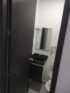 een badkamer met een wastafel, een toilet en een spiegel bij Hermoso aparta estudio con Aire Acondicionado en un primer piso Cerca al Hospital de Neiva in Neiva