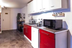 a kitchen with red cabinets and a microwave at Le Factory proche aéroport CDG I Paris I Astérix in Moussy-le-Neuf