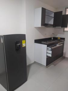 een keuken met een zwarte koelkast en een wastafel bij Hermoso aparta estudio con Aire Acondicionado en un primer piso Cerca al Hospital de Neiva in Neiva