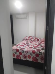 a bedroom with a bed with a red and white comforter at Hermoso aparta estudio con Aire Acondicionado en un primer piso Cerca al Hospital de Neiva in Neiva