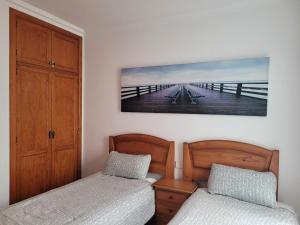 a bedroom with two beds and a picture of a pier at ISLOTE in Famara