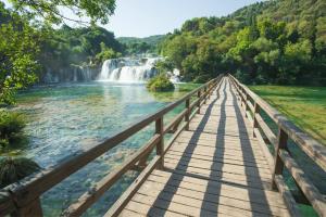 a wooden bridge over a river with a waterfall at Ted's Luxury Place with jacuzzi in Šibenik