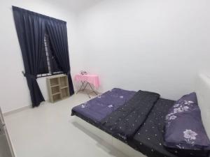 Un dormitorio con una cama con sábanas moradas y una mesa. en BB D'VELODROM Homestay Dungun, en Dungun