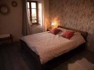 een slaapkamer met een bed met 2 rode kussens bij Chambre d'hôte de L'Auberge de la Fruitière in Vers