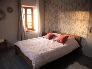een slaapkamer met een bed met twee rode kussens erop bij Chambre d'hôte de L'Auberge de la Fruitière in Vers