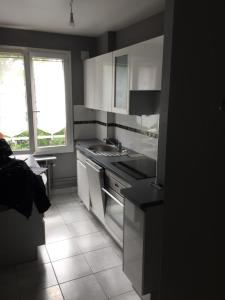 - une cuisine noire et blanche avec évier et cuisinière dans l'établissement Superbe appartement, résidence familiale, parking, à Chevilly-Larue