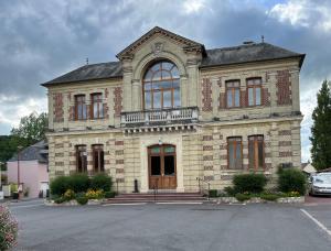 een groot bakstenen gebouw met een balkon op een parkeerplaats bij Maison de la Calonne - Riverside house & terrace in Cormeilles