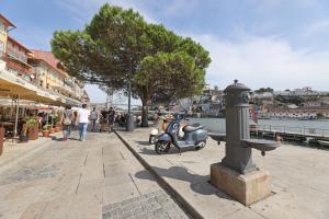 un scooter estacionado en una acera cerca del agua en FLH Almada Cozy Apartment with View, en Oporto