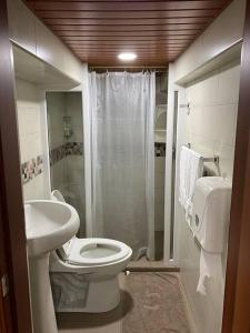 y baño con aseo, lavabo y ducha. en Hermoso apartamento en Baños de Agua Santa, en Baños