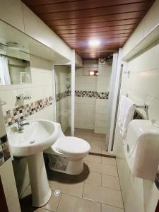 a bathroom with a white toilet and a sink at Hermoso apartamento en Baños de Agua Santa in Baños