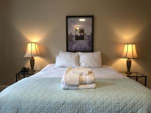 a bed with two lamps and a towel on it at Leaside Executive Apartments in St. John's