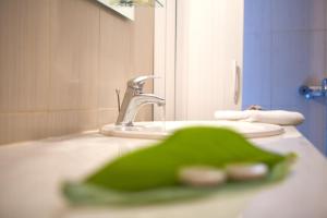 un lavandino in bagno con oggetto verde di fronte a uno specchio di Anemolia Apartments a Vassiliki