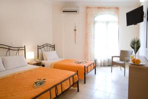 a hotel room with two beds and a television at Anemolia Apartments in Vasiliki