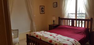 a bedroom with a bed with a red comforter and a window at Mazotos Panoramic Village in Mazotos