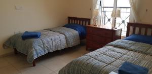 a bedroom with two beds and a dresser and a window at Mazotos Panoramic Village in Mazotos