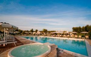 a large swimming pool with chairs and umbrellas at Riva di Palo Beach Hotel in Ladispoli
