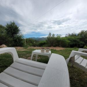 dos bancos blancos y una mesa en un campo en Bella Vista en Valle Hermoso