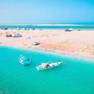 two boats sitting in the water next to a beach at Belle appartement vue de mer in Zarzis