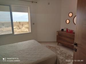 a bedroom with a bed and a window and a dresser at Belle appartement vue de mer in Zarzis