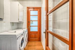 a laundry room with a washing machine and a door at LA CALMA Espectacular villa con jardín y piscina en Menorca in S'Algar