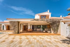 a villa with a patio and a house at LA CALMA Espectacular villa con jardín y piscina en Menorca in S'Algar