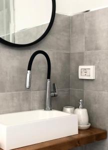 uma casa de banho com um lavatório branco e um espelho. em Dèpendance immersa tra gli ulivi em Cologna