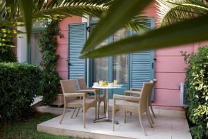 Anemolia Apartments في فاسيليكي: طاولة وكراسي أمام منزل وردي