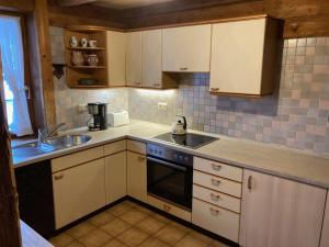 a small kitchen with white cabinets and a sink at Knusperhäusle Reckenberg in Bad Hindelang