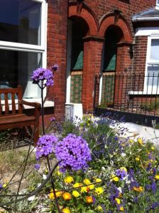 um jardim com flores roxas em frente a um edifício em The Anchorage , Gorleston on Sea em Gorleston-on-Sea