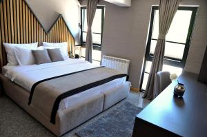 a bedroom with a large white bed and large windows at Modern Mountain in Kolašin