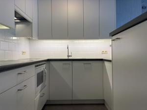 uma cozinha com armários brancos e um lavatório em Sea Horse 0401 em Nieuwpoort