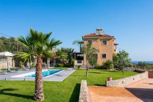 a villa with a swimming pool and a palm tree at Villa David Heraklion in Kavrokhórion