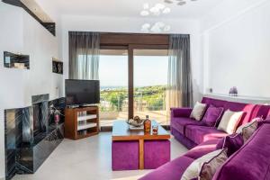salon z fioletową kanapą i telewizorem w obiekcie Villa David Heraklion w mieście Kavrokhórion