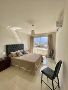 a bedroom with a bed and a window and a chair at Opera Villa Carlos Paz in Villa Carlos Paz