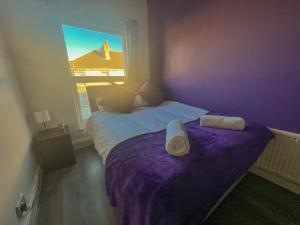 a purple bedroom with two beds and a window at Spacious and perfectly located 4-bedroom Apartment in Liverpool