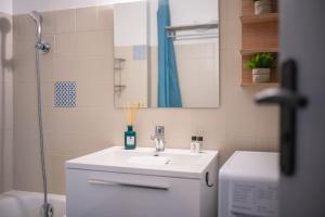 La salle de bains blanche est pourvue d'un lavabo et d'une douche. dans l'établissement Cosy Studio près des Palaces Mentonnais, à Menton