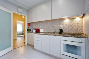 uma cozinha com armários brancos e uma bancada em APOSENTUS - Serenity 1D no Porto