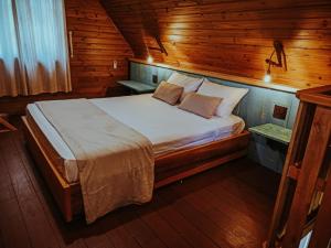 a bedroom with a bed in a wooden cabin at Hospedaria Locanda 65 - Garibaldi - Serra Gaúcha in Garibaldi