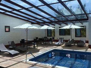 un patio con piscina, mesas y sombrillas en Cabañas Mazzatl 6 pax en Mazamitla