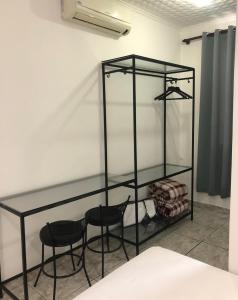 estante de cristal con 2 sillas negras en una habitación en Hotel Pigalle, próximo a Expo São Paulo, en São Paulo