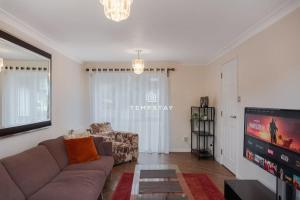 a living room with a couch and a flat screen tv at Spacious 5 bed Sunninghill with driveway parking in Ascot