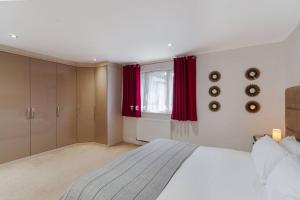 a bedroom with a large bed with red curtains at Spacious 5 bed Sunninghill with driveway parking in Ascot