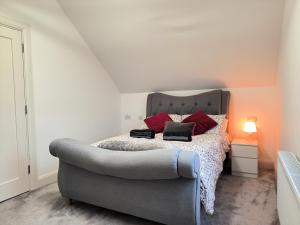 a bedroom with a bed with red pillows and a couch at Home Close to Center Parcs Longford 