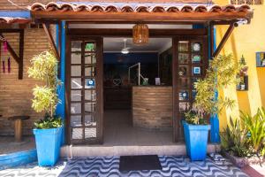 an entrance to a building with two blue potted plants at Pousada Ecos do Mar in Praia do Frances