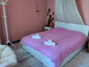 a bedroom with a pink bed with two towels on it at Comfortable Central Appartment by a park in Larisa