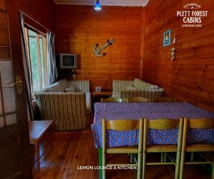 una sala da pranzo con tavolo, sedie e chitarra di Plett Forest Cabins a Plettenberg Bay