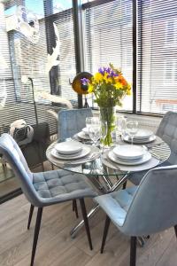 a dining room table with a vase of flowers on it at The Copperfield Apartment - Broadstairs Central - By Goldex Coastal Breaks in Kent